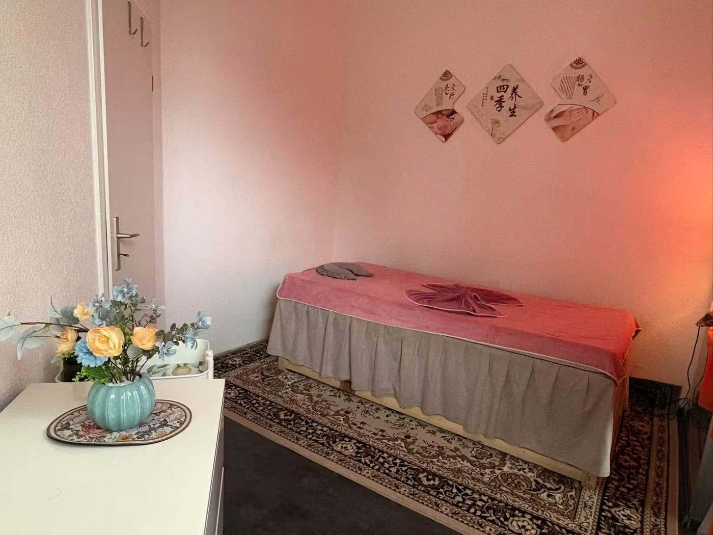 Behandlungsraum bei Shufu Massage mit Massageliege, warmem Licht und dekorativen Blumen